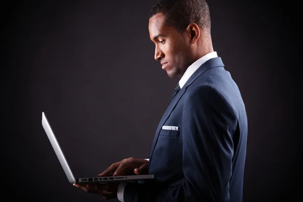 Negócios homem negro whit laptop no fundo preto — Fotografia de Stock