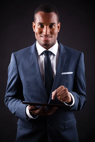 Young business man with a digital tablet on black background — Stock Photo, Image