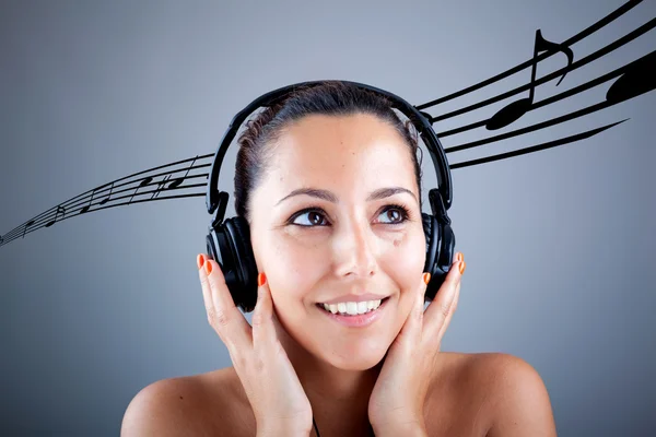 Beautiful girl with headphones and musical notes flying on grey — Stock Photo, Image