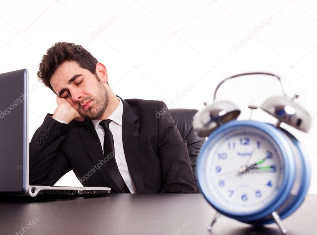 Tired young businessman sleeping next laptop on white background