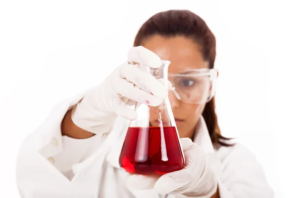 Femme scientifique regardant une fiole de liquide, isolée sur du blanc — Photo