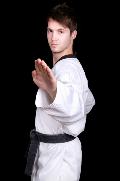 Junger Mann praktiziert Kampfkunst vor schwarzem Hintergrund — Stockfoto