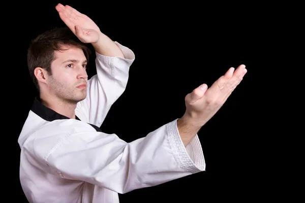 Young man practicing martial arts over black background — Stock Photo, Image