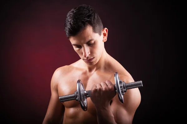 Bilden av en muskulös ung man lyfta vikter på svart bak — Stockfoto