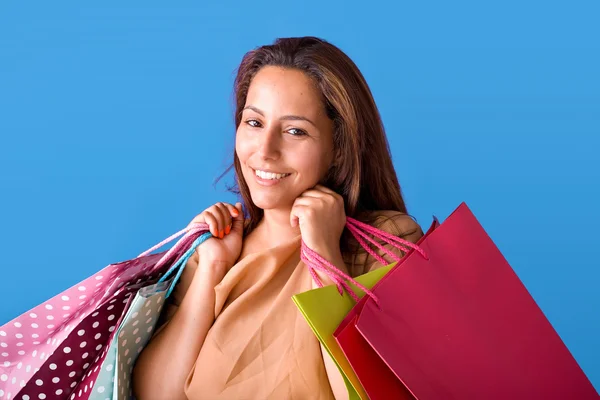 Portrait of a beautiful young woman holding shopping bags over b — Stock Photo, Image