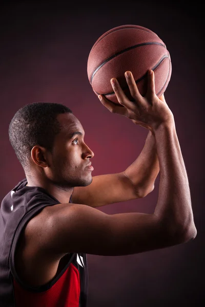 Jonge mannelijke basketbalspeler tegen zwarte achtergrond — Stockfoto