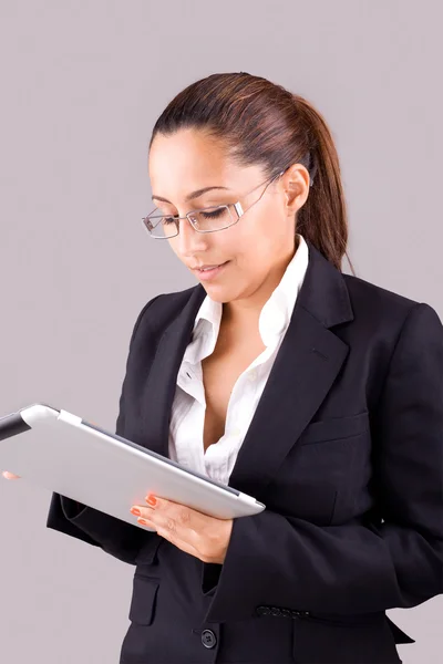 Молода усміхнена бізнес-леді з планшетним комп'ютером на сірому фоні — стокове фото