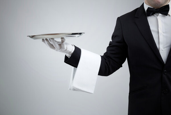 Waiter holding empty silver tray over gray background