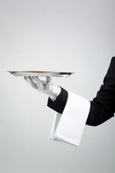 Kelner przytrzymanie puste srebrna taca na szarym tle — Zdjęcie stockowe