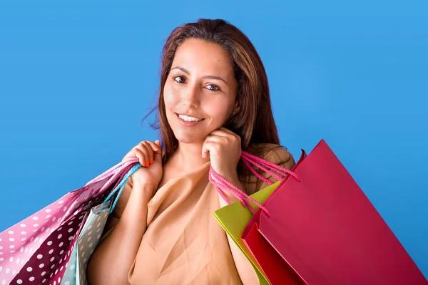 Mooie jonge vrouw houdt van boodschappentassen, geïsoleerd op blauwe st — Stockfoto