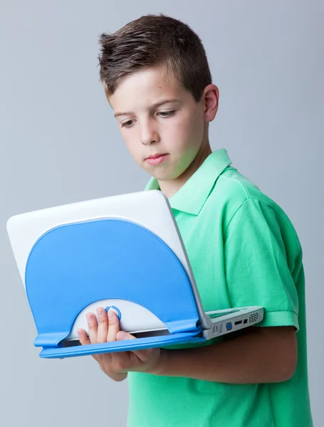 Llittle pojke med laptop mot grå bakgrund — Stockfoto