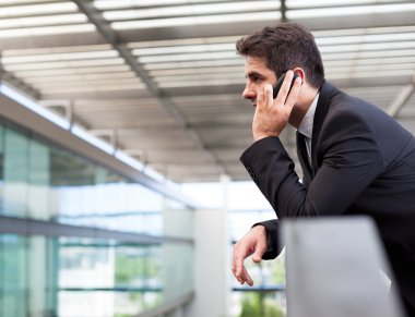 Modern ofiste cep telefonuyla konuşan genç bir iş adamı.
