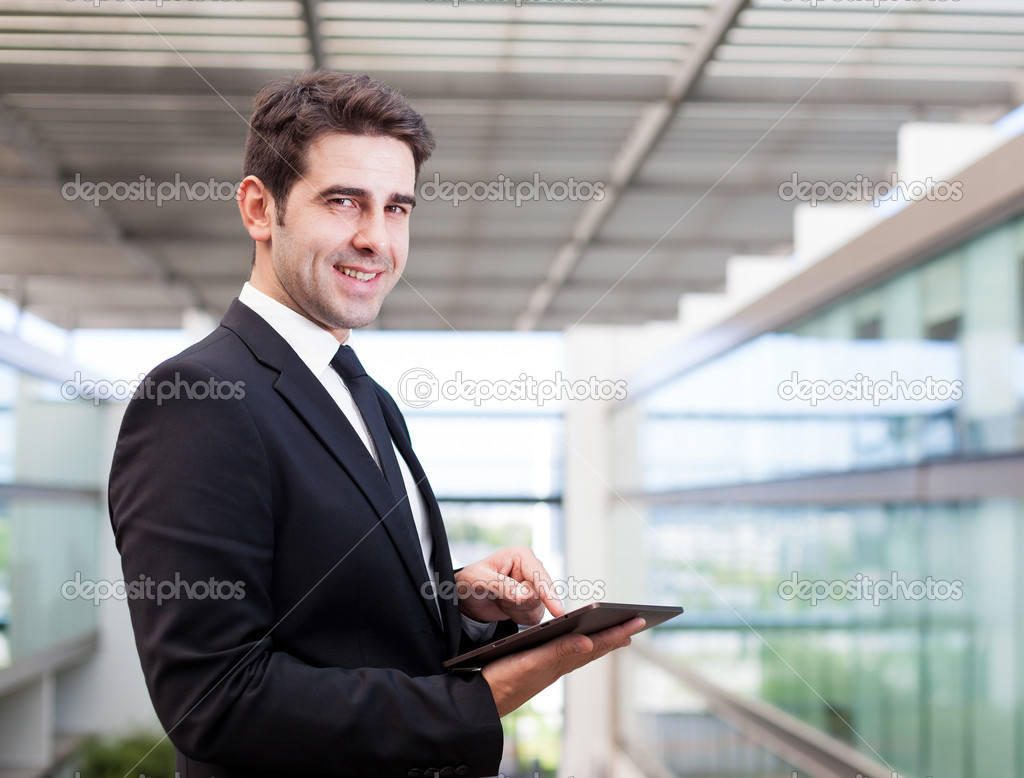 Smiling young businessman using his digital tablet at the office
