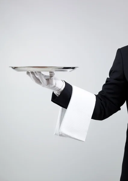 Waiter holding empty silver tray over gray background — Stock Photo, Image