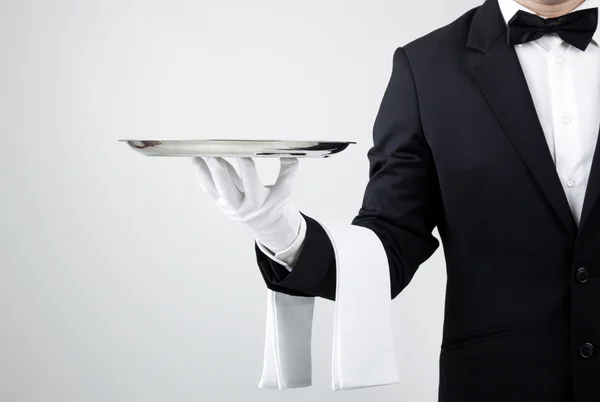 Waiter holding empty silver tray over gray background — Stock Photo, Image