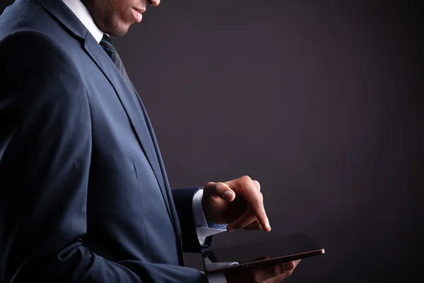 Empresário segurando tablet digital em fundo preto — Fotografia de Stock