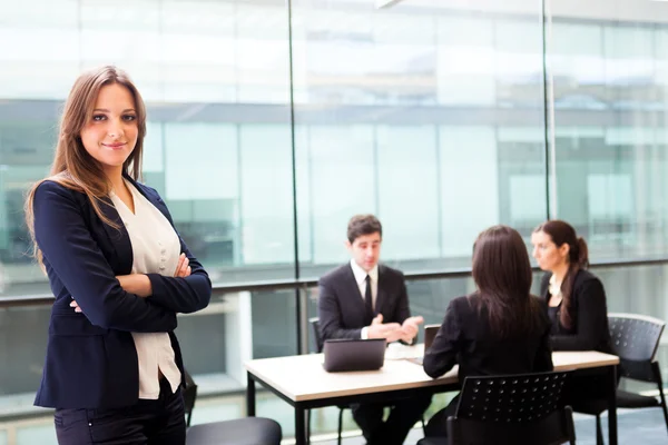 Hermosa mujer de negocios sonriendo con sus colegas detrás — Foto de Stock