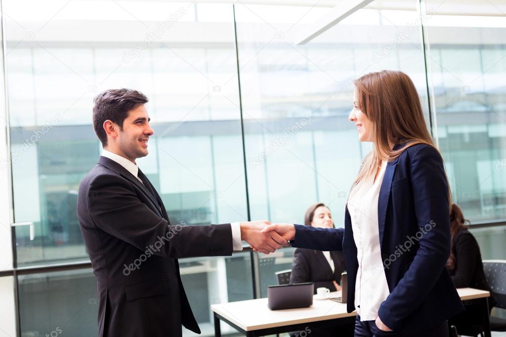Business handshake at modern office with bussiness on bac