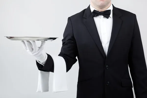 Waiter holding empty silver tray over gray background — Stock Photo, Image