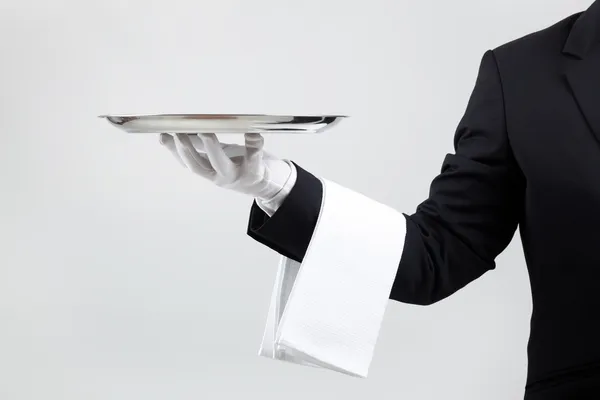 Waiter holding empty silver tray over gray background — Stock Photo, Image