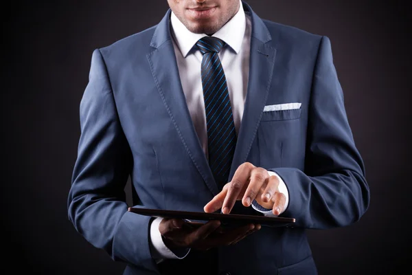 Businessman working on a digital tablet against black backgroun — Stock Photo, Image