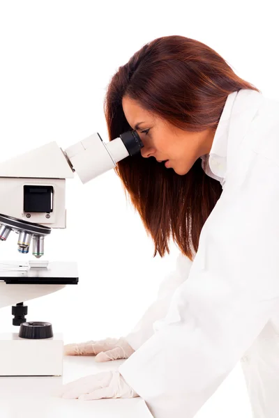 Young female researcher looking into a microscope, isolated on w — Stock Photo, Image