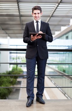 ofiste onun dijital tablet kullanarak gülümseyen genç işadamı