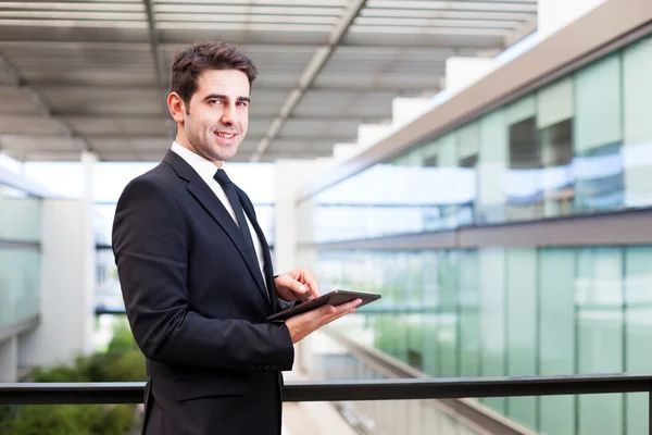 Glücklich lächelnder junger Geschäftsmann mit seinem digitalen Tablet an der — Stockfoto