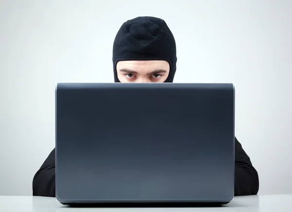 Retrato de um hacker com balaclava contra fundo cinza — Fotografia de Stock