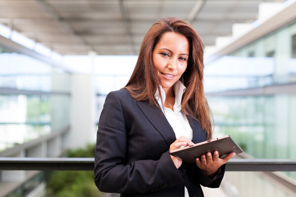 Улыбающаяся деловая женщина, использующая планшетный компьютер в офисе
