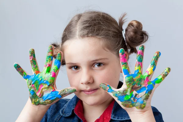 Beautiful little girl showing painted hands over grey background — Stock Photo, Image