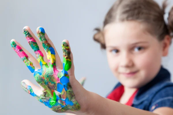 Beautiful little girl showing painted hands over grey background — Stock Photo, Image