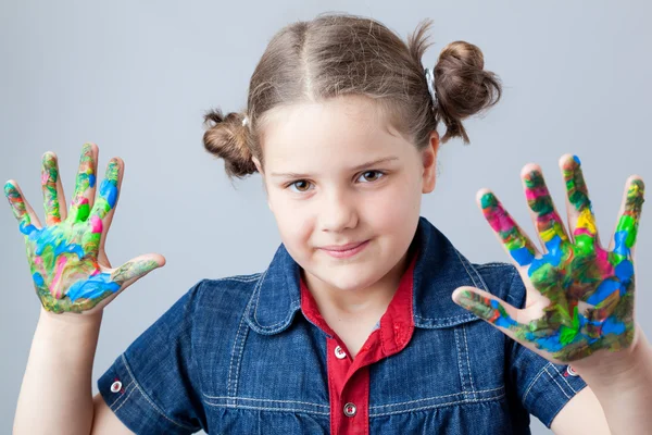 Beautiful little girl showing painted hands over grey background — Stock Photo, Image