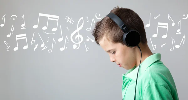 Bonito menino adolescente ouvindo música em fones de ouvido sobre bac cinza — Fotografia de Stock