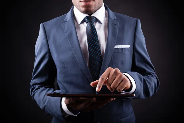 Empresário trabalhando em um tablet digital contra backgroun preto — Fotografia de Stock