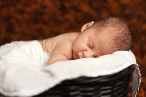 Close-up of adorable baby boy sleeping in a basket — Stock Photo, Image