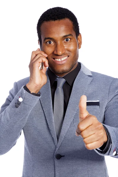Szczęśliwy uśmiechający się młody biznesmen rozmawia przez telefon i gestykulacji kciuk w górę — Zdjęcie stockowe