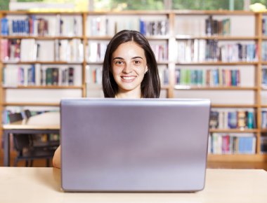 gülümseyen kız öğrencinin lise LIBR içinde laptop ile çalışma