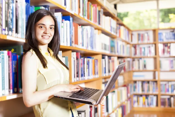 Estudante sorridente com laptop em uma biblioteca do ensino médio — Fotografia de Stock