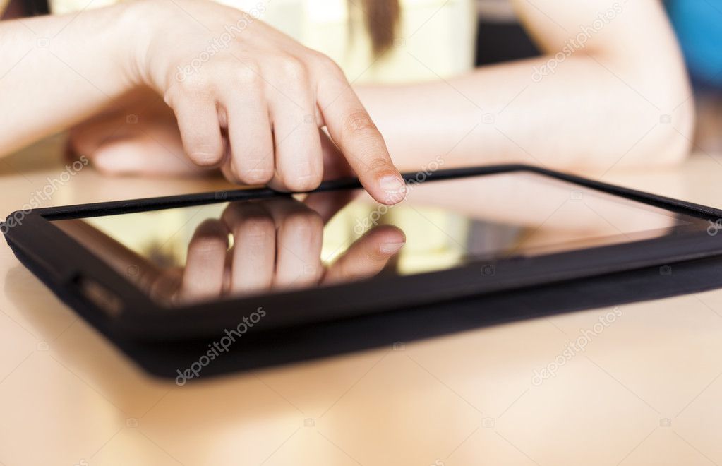 Close up of female student typing on tablet at the library