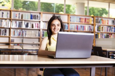 gülümseyen kız öğrencinin lise LIBR içinde laptop ile çalışma