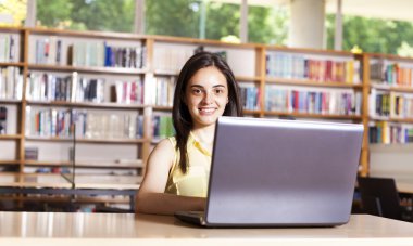 gülümseyen kız öğrencinin lise LIBR içinde laptop ile çalışma