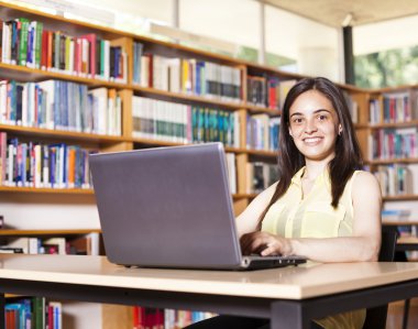 gülümseyen kız öğrencinin lise LIBR içinde laptop ile çalışma