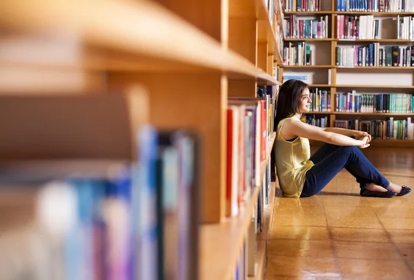 Menina bonita pensativo sentado na biblioteca da faculdade — Fotografia de Stock