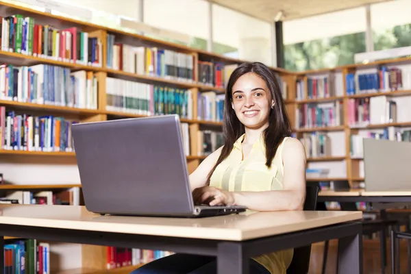 Estudante do sexo feminino sorrindo trabalhando com laptop em uma libra do ensino médio — Fotografia de Stock