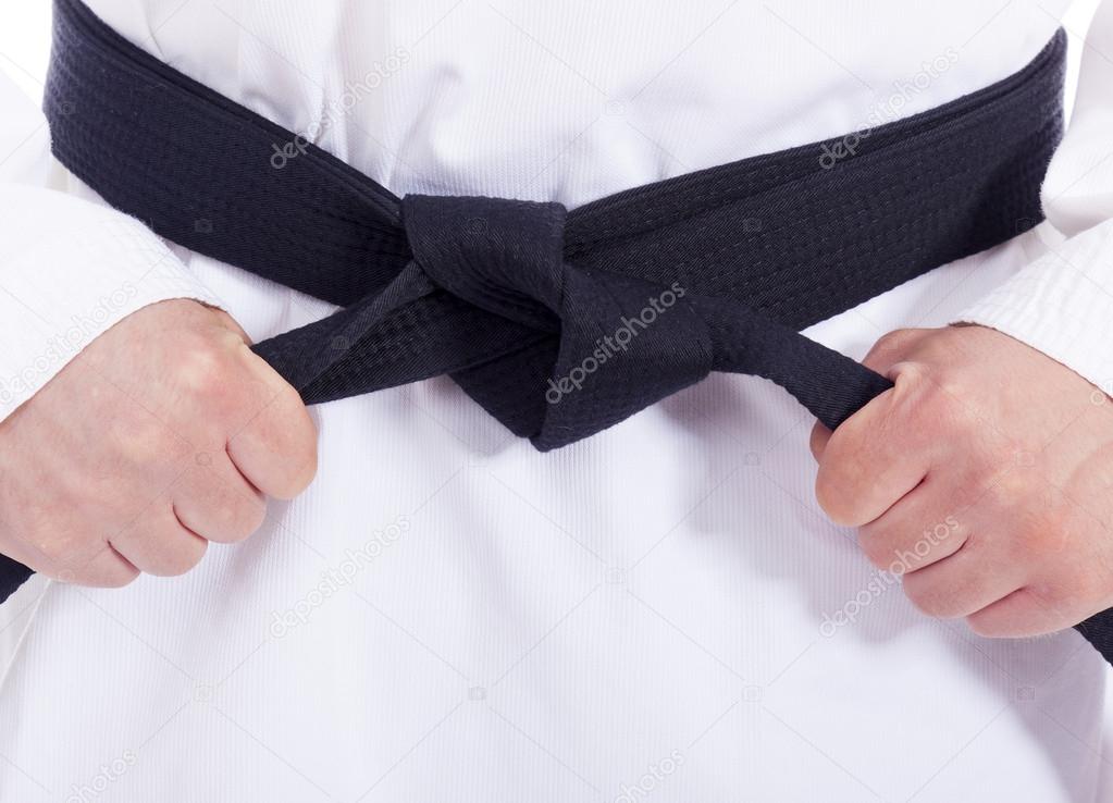 Closeup of a martial arts man tying his black belt