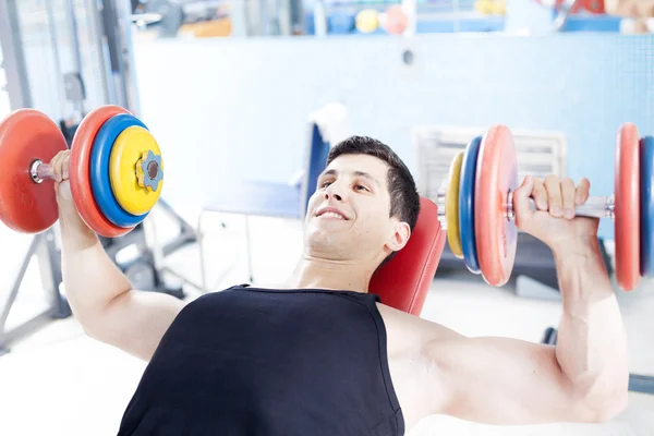 Joven hombre guapo levantando pesas libres pesadas en el gimnasio —  Fotos de Stock