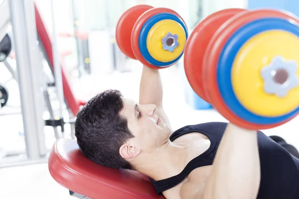 Young handsome man lifting heavy free weights at the gym — Stock Photo, Image