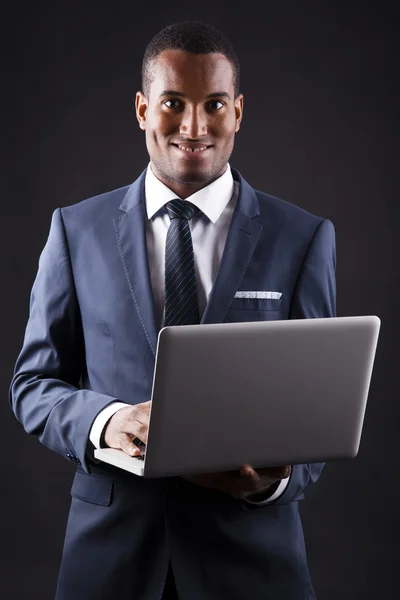 Sorrindo negócio homem negro whit laptop no fundo preto — Fotografia de Stock