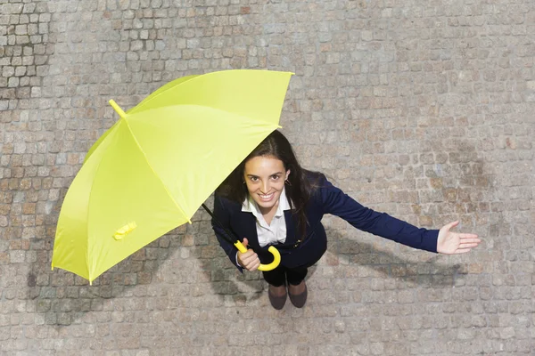 Smiling young business woman with yellow umbrella checking if it's rainin — Stock Photo, Image